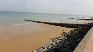 A beach with a rocky breakwater, calm sea, and clear sky. - 3 bedroom accommodation in Sheringham (Sheringham)