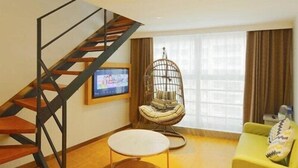 A living room with a wooden staircase, a round table, a yellow sofa, and a hanging chair. - Greentree Inn Shanghai Qipu Road Tiantong Road Subway Station Express Hotel (Shanghai)