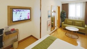 A hotel room with a bed, a television mounted on the wall, a small table, a sofa, and a plant. - Greentree Inn Shanghai Qipu Road Tiantong Road Subway Station Express Hotel (Shanghai)