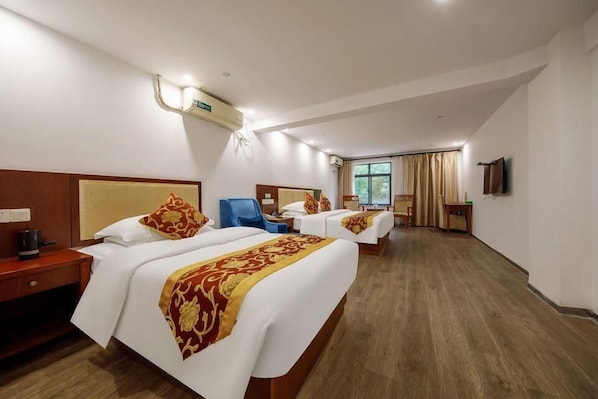 A hotel room with two beds, a desk, a chair, a TV, and a window with curtains.