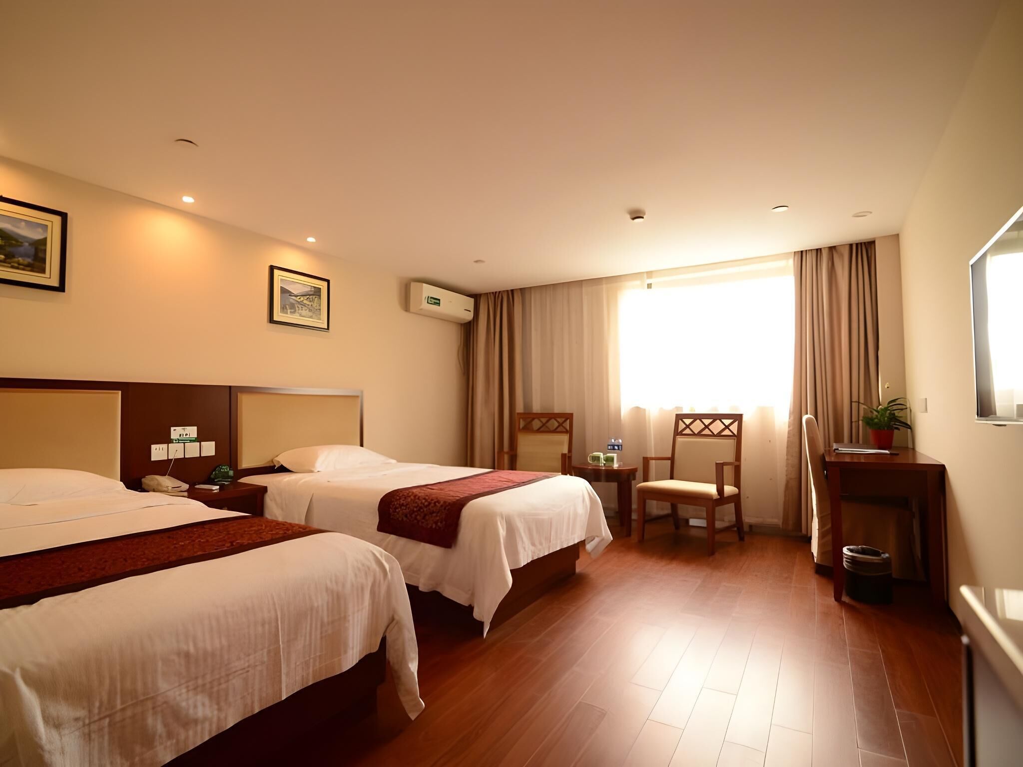 A hotel room with two beds, a desk, a chair, and a small table.