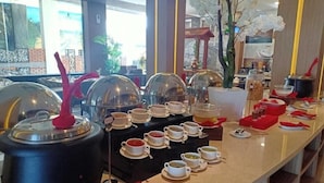 A buffet setup with various food items and beverages, including hot pots and tea cups, arranged on a counter. - Sonaview Hotel (Dumai)