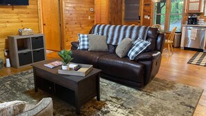 A cozy cabin interior with a leather sofa, a small coffee table, and a wooden cabinet. - The Hygge at Blue Ridge - Beautiful Mtn view, 3 Fire types, Hot Tub (Blue Ridge)