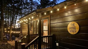 A wooden cabin with a porch, string lights, and a sign that reads "THE HYGGE BLUE RIDGE, GA". - The Hygge at Blue Ridge - Beautiful Mtn view, 3 Fire types, Hot Tub (Blue Ridge)