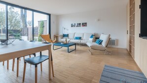 Una sala de estar moderna con comedor, ventanas amplias y vistas al exterior.