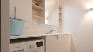 Un baño moderno con lavamanos blanco, espejo e lavadora integrada.