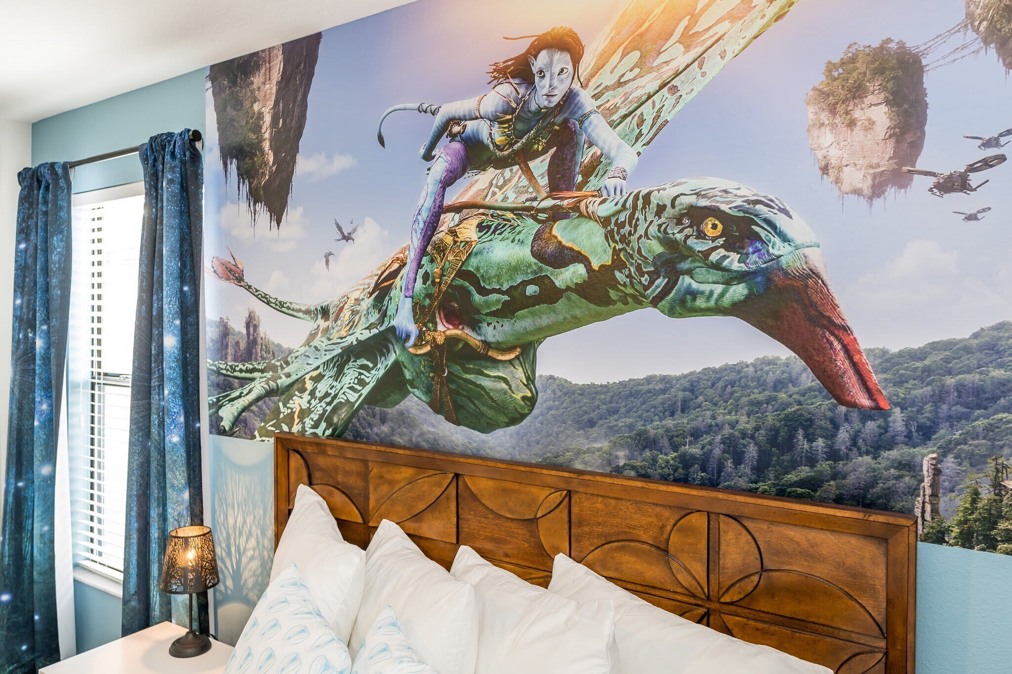 A bedroom with a mural of a fantasy scene, a bed with white pillows, and a nightstand with a lamp.