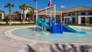Un espace de jeux aquatiques avec des toboggans et une piscine, entouré de palmiers et de bâtiments.