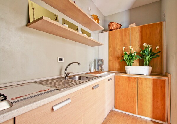 A modern kitchen with wooden cabinets, a stainless steel sink, and a countertop with a cutting board.
