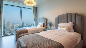Une chambre d’hôtel moderne avec un grand lit, un plus petit lit et une vue sur le paysage urbain grâce à de grandes fenêtres.