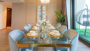 Un coin repas avec une table en verre, six chaises bleu clair et un lustre.