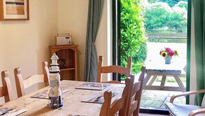 Un comedor con una mesa de madera, sillas, una radio y vistas al exterior con vegetación.
