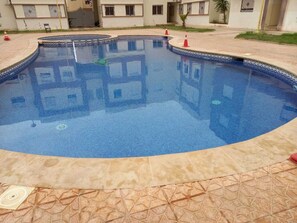 A swimming pool with a tiled edge and a patterned floor. - Pool view apartment for your vacation (Saidia)