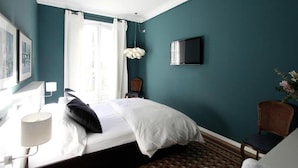 A hotel room with a bed, a TV mounted on the wall, a window with curtains, a chair, and a lamp. - Bed and Break Barcelona (Barcelona)
