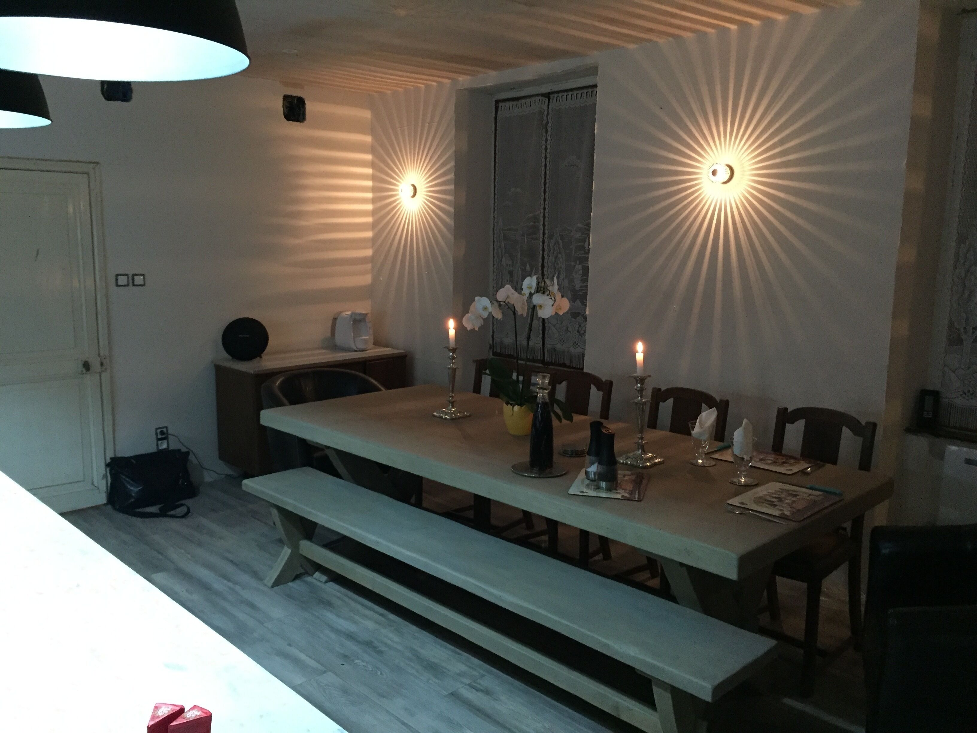 A dining area with a long table, benches, candles, and a vase with flowers.