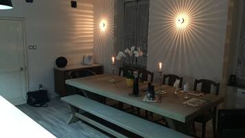 A dining area with a long table, benches, candles, and a vase with flowers.