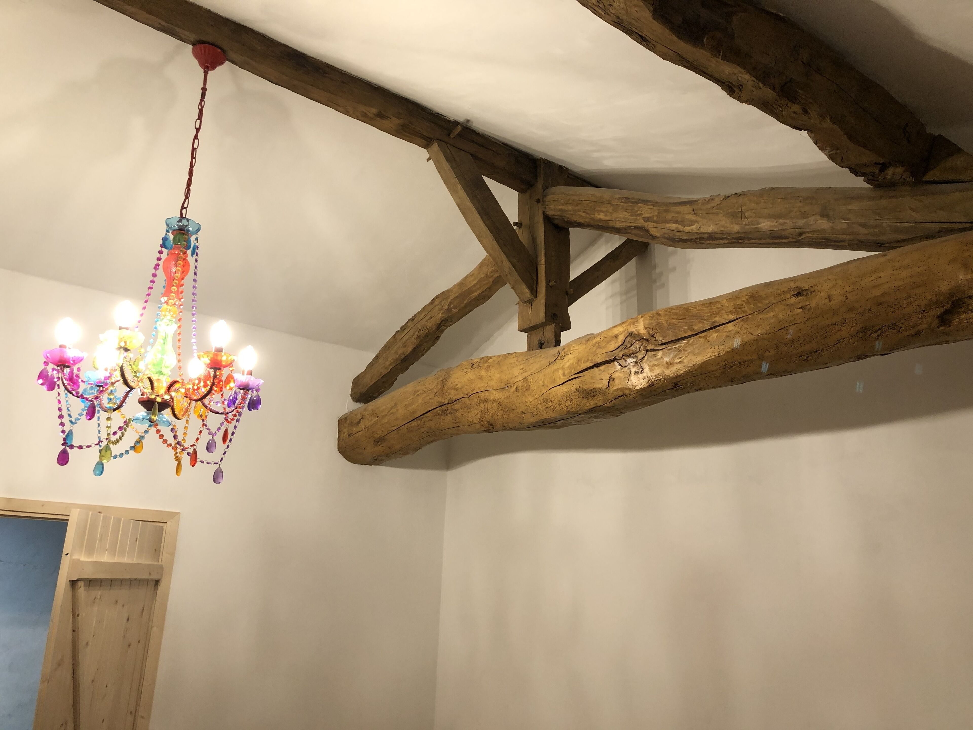 Een kroonluchter met meerdere lampen die aan een houten balk hangt.