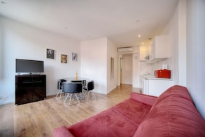 A modern apartment with a living room, dining area, kitchenette, and a TV.