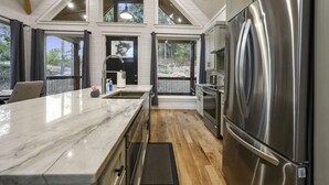 A modern kitchen with a large island, stainless steel appliances, and a view of the outdoors.
