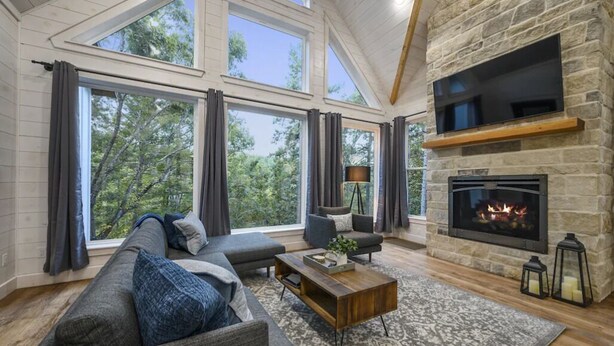 A spacious living room with a stone fireplace, large windows, and a cozy seating area.