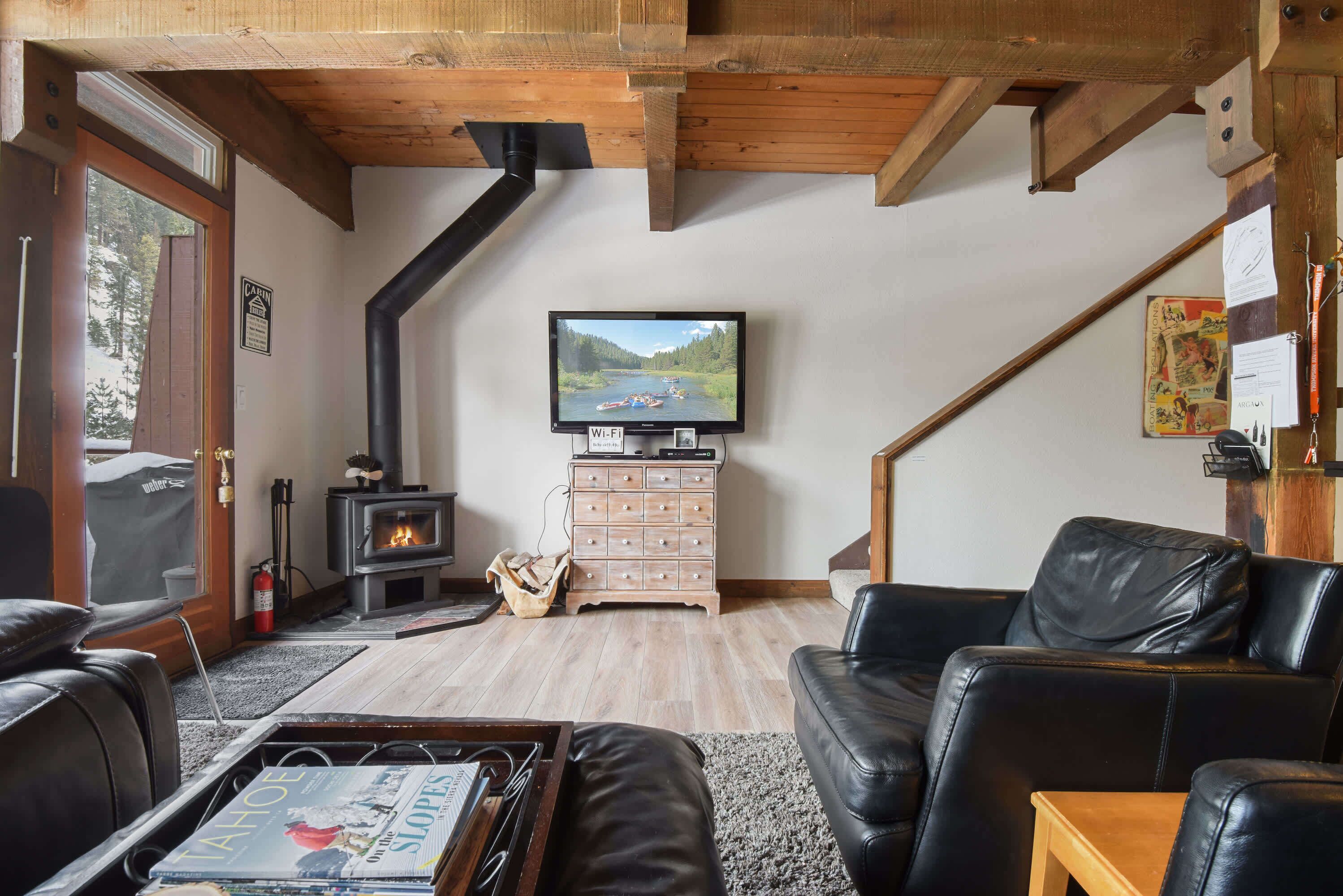 Ein gemütliches Wohnzimmer mit Kamin, Ledersofas, Fernseher und Holzboden.