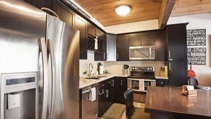 A modern kitchen with stainless steel appliances, dark cabinetry, and a wooden ceiling. - Alpine Manor Retreat Mountain Relaxation (Olympic Valley)