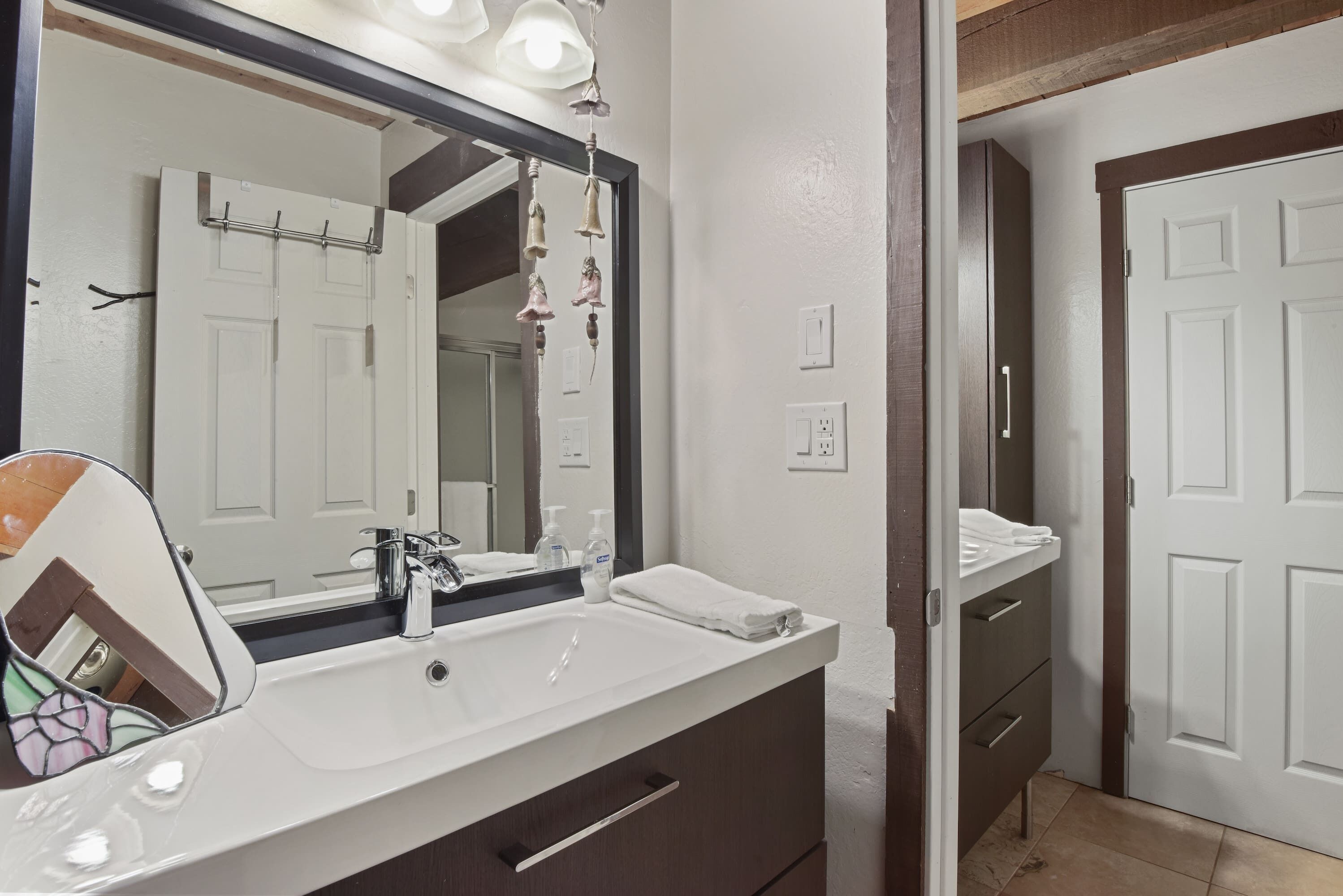 A bathroom with a white sink, a mirror, and a door.