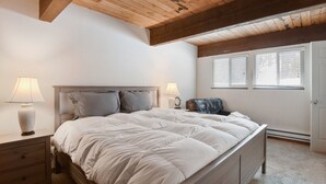 A bedroom with a bed, nightstands, a lamp, and a window. - Alpine Manor Retreat Mountain Relaxation (Olympic Valley)