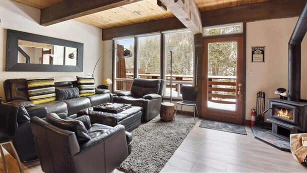 A cozy living room with leather sofas, a fireplace, and large windows offering a view of the outdoors. - Alpine Manor Retreat Mountain Relaxation (Olympic Valley)