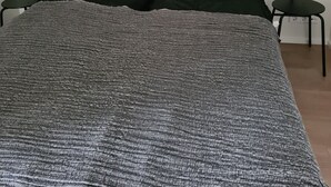 Ein Schlafzimmer mit einem großen Bett, zwei Nachttischen und einer schlichten Wand.