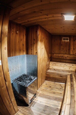 Ein Holzhütten-Interieur mit einem Metallofen, Holzwänden und einer geneigten Decke.