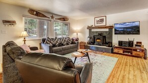 A cozy living room with a fireplace, a sofa, a leather chair, and a TV. - Coziness Cabin - Cute Little Cabin in the Tahoe Woods! (South Lake Tahoe)