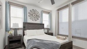 Ein Schlafzimmer mit einem Bett, Nachttischen, einer Wanduhr und einem Deckenventilator.