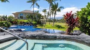 Ein Poolbereich mit einem klaren, blauen Pool, einer steinverkleideten Kante und einem Haus im Hintergrund.