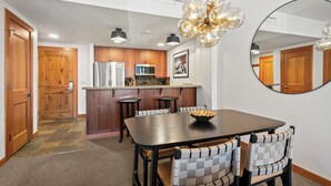 Una cocina moderna con armarios de madera, una isla central y un comedor con una mesa oscura y sillas a cuadros.