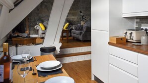 A modern kitchen with white cabinets, a wooden countertop, and a dining area with a table set for two. - 2 bedroom accommodation in Criccieth (Criccieth)