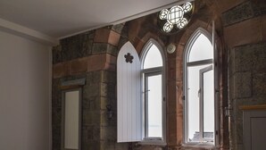 A bedroom with stone walls, a bed, a window with a white door, and a wooden shelf. - 2 bedroom accommodation in Criccieth (Criccieth)
