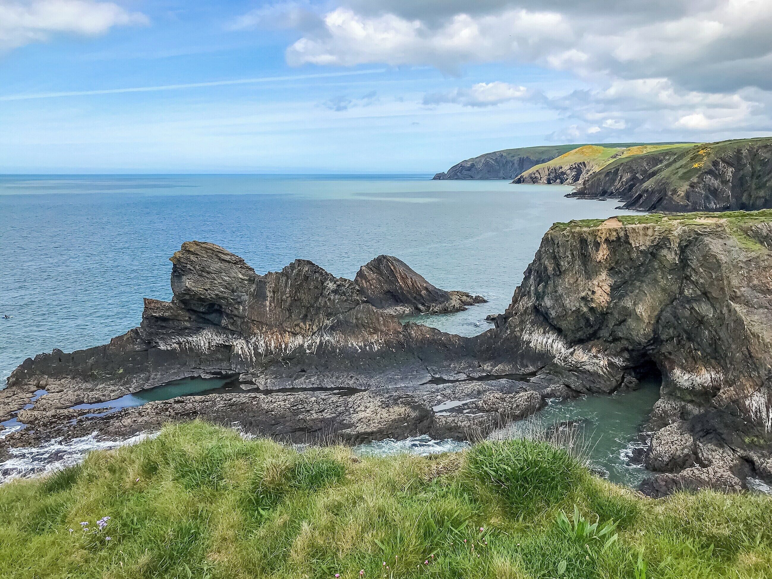 A coastal landscape with rocky cliffs and a clear view of the sea.