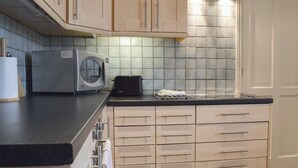 A kitchen with a microwave, toaster, and a tiled backsplash. - 1 bedroom accommodation in Clopton, near Kettering (Clopton, near Kettering)