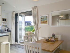 Eine moderne Küche mit einem Holztisch, weißen Stühlen und Blick ins Freie.