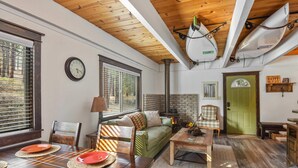 Een knusse woonkamer met een houten plafond, een groene deur en een open haard.