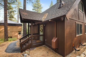 A wooden cabin with a porch, a fireplace, and a stone pathway leading to the entrance. - Incline Cottage Year-round Outdoor Fun! (Incline Village)