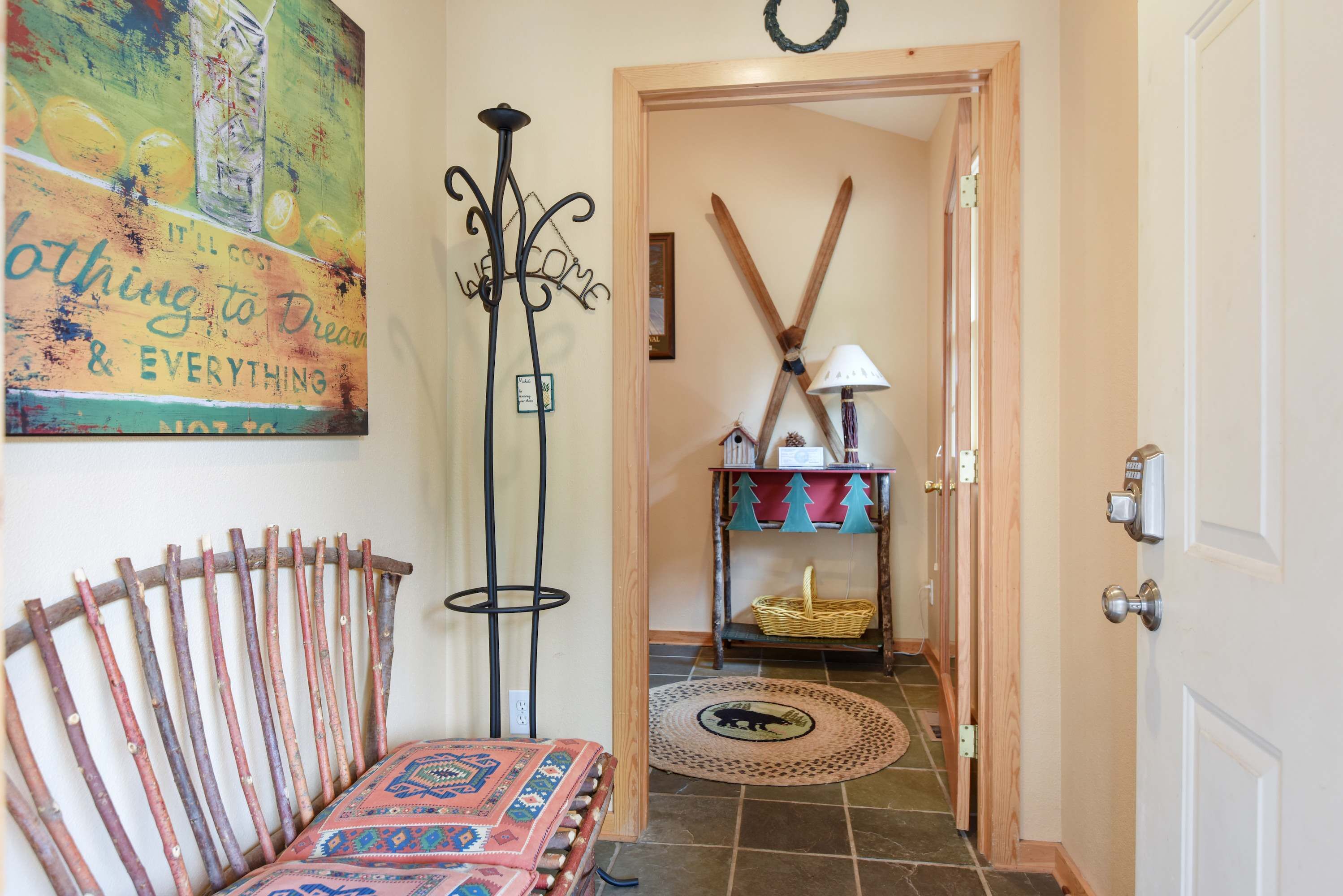 Un pasillo con un banco de madera rústica, un soporte metálico decorativo y una obra de arte llamativa en la pared.
