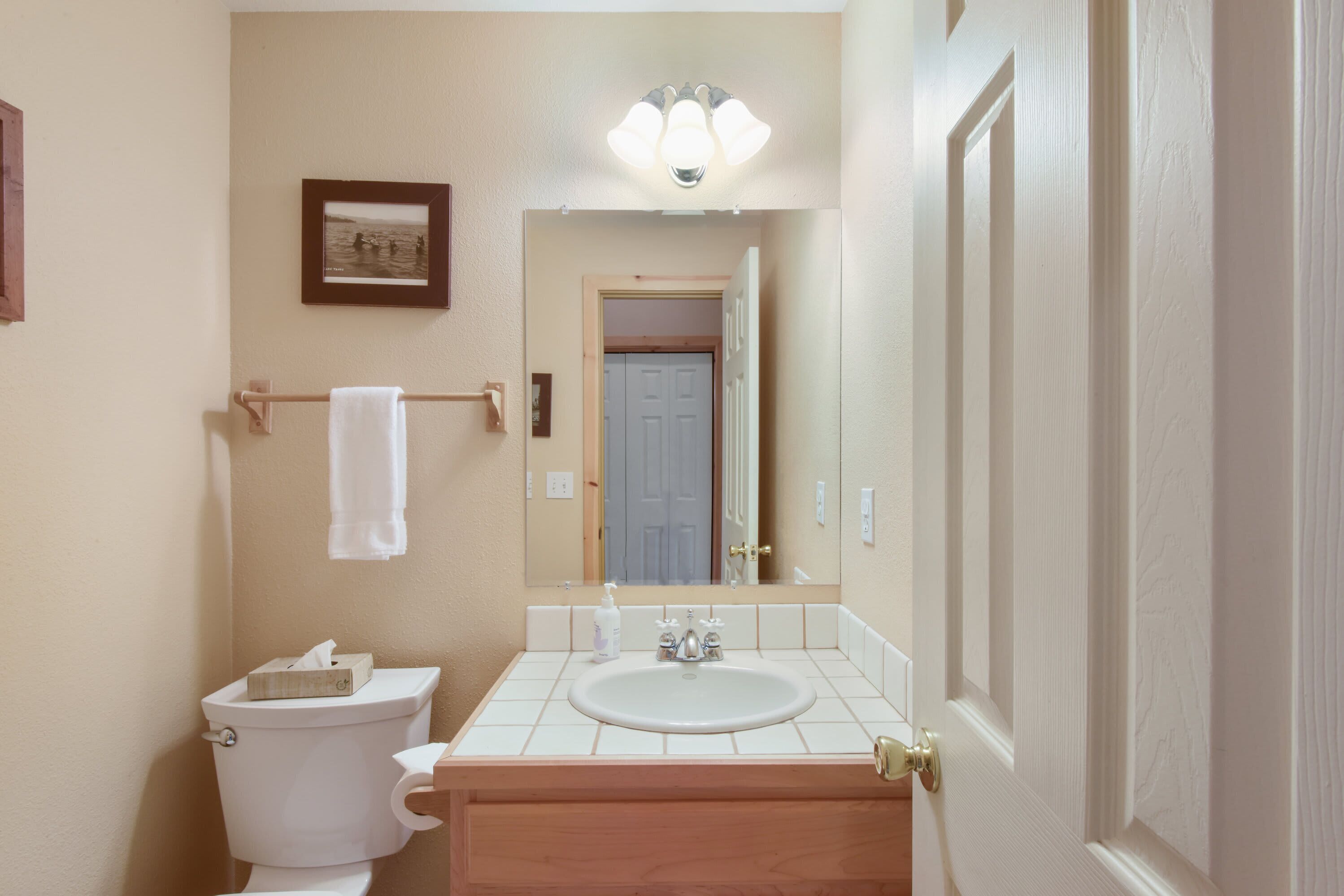 A bathroom with a toilet, sink, and mirror.