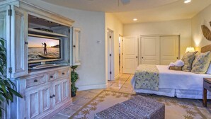 A bedroom with a bed, a television mounted on a cabinet, a ceiling fan, and a door leading to another room. - Luxurious Mykonos - Pet Friendly (Santa Barbara)