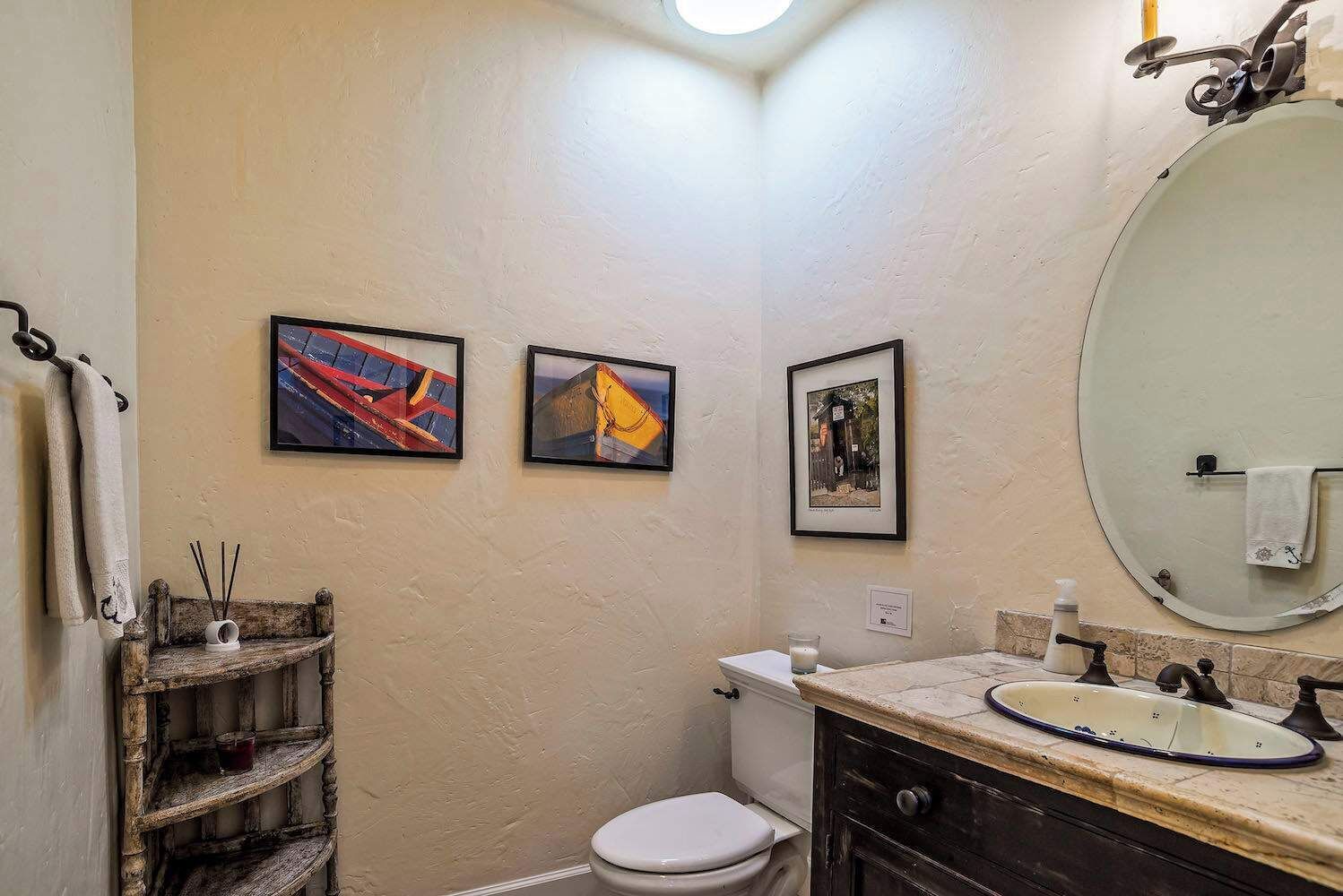 Un baño con inodoro, lavabo y dos cuadros en la pared.