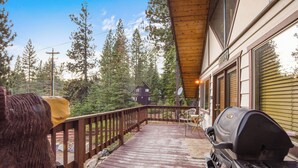 Un patio in legno con una griglia, una sedia e una cabina sullo sfondo.