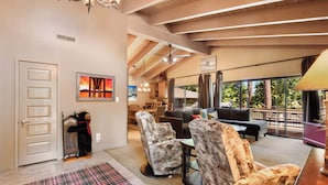 A spacious living area with a high ceiling, a fireplace, and a view of the outdoors. There are multiple seating options including a sofa and chairs. - Waters Edge Oasis Shared Pool & Pier Access (Tahoma)