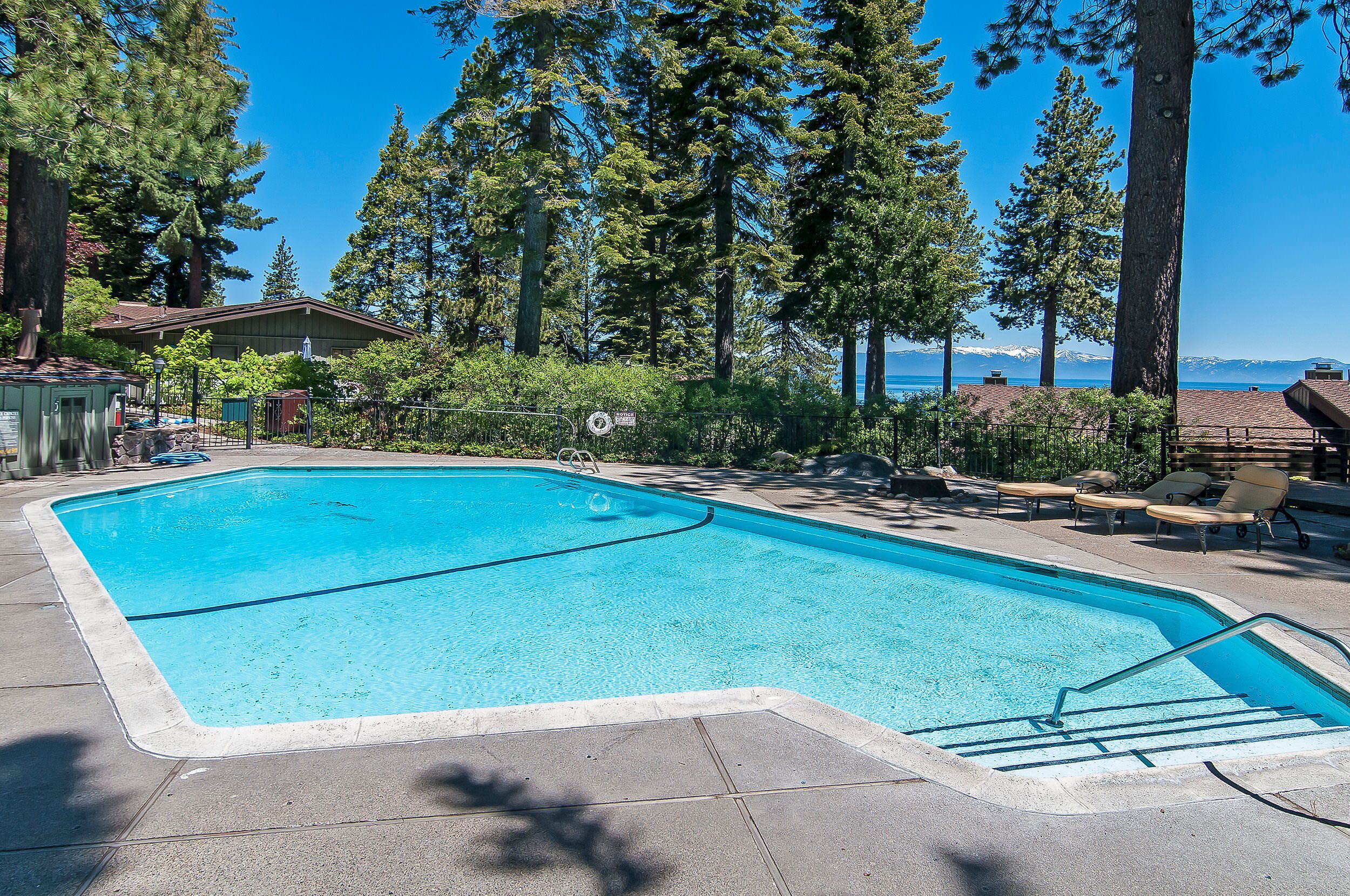 Une piscine rectangulaire à l’eau d’un bleu limpide, entourée d’une terrasse en béton, et offrant une vue sur une chaîne de montagnes en arrière-plan.