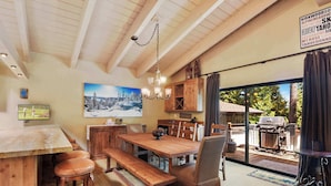 A wooden dining area with a large table, benches, and a chandelier. - Waters Edge Oasis Shared Pool & Pier Access (Tahoma)